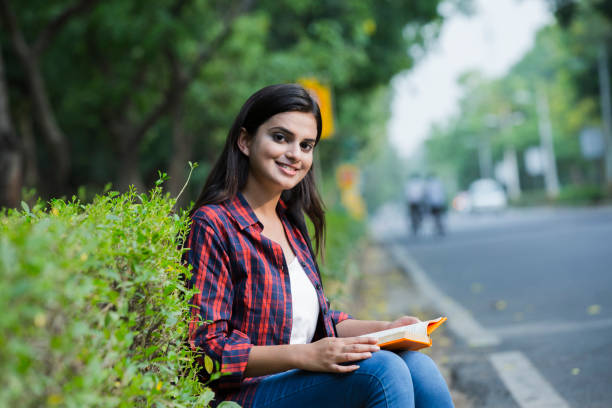 A young woman reading a book outdoors, symbolizing self-paced learning and personal growth in an LMS environment.